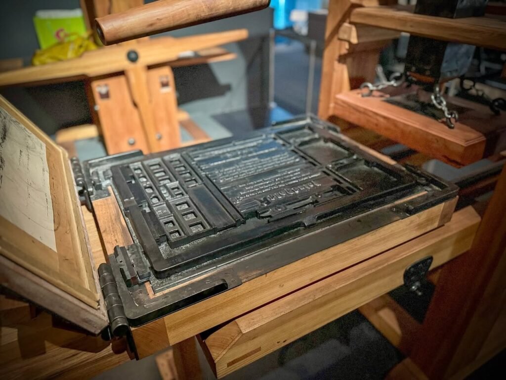 A multi-angle view of a traditional letterpress printing machine with wooden frames and metal type blocks.