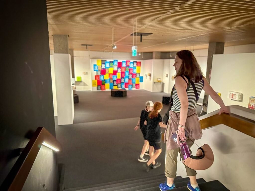 People walking through a modern interior space towards a vibrant, multi-colored tiled wall installation.