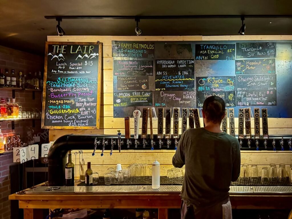 A view of The Lair's beer selection displayed on blackboards behind a bar counter.