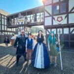 A family posing in front of a historic Tudor-style building at a medieval themed festival.