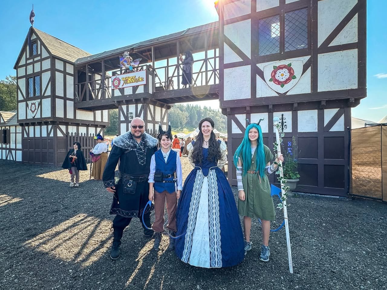 First Ren Faire A family posing in front of a historic Tudor-style building at a medieval themed festival.