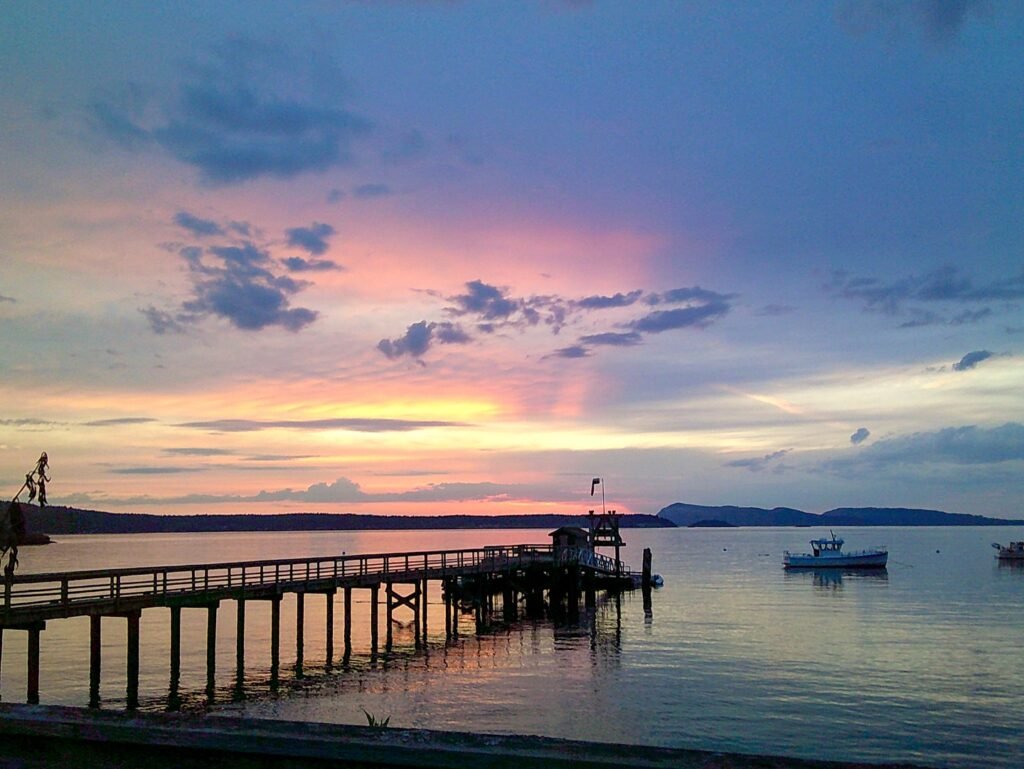 Stunning sunset over a calm bay with a long wooden pier stretching into the water.