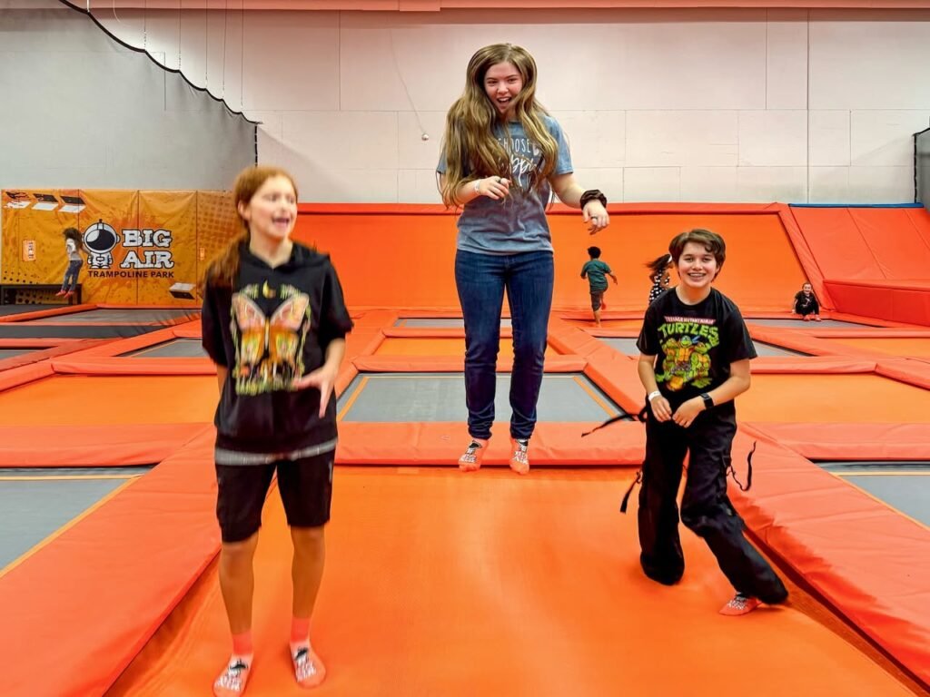 People enjoying time on orange trampolines at the Big Air trampoline park.