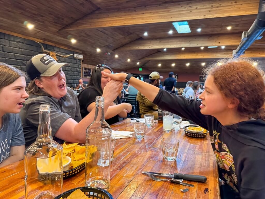 Friends sharing a lively moment over nachos and drinks in a rustic restaurant.