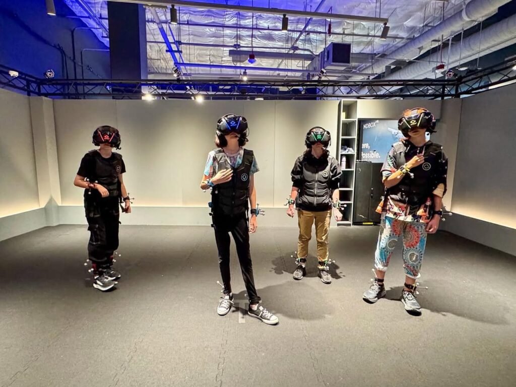 A group wearing motion capture suits stands in a room with a motion capture ceiling.