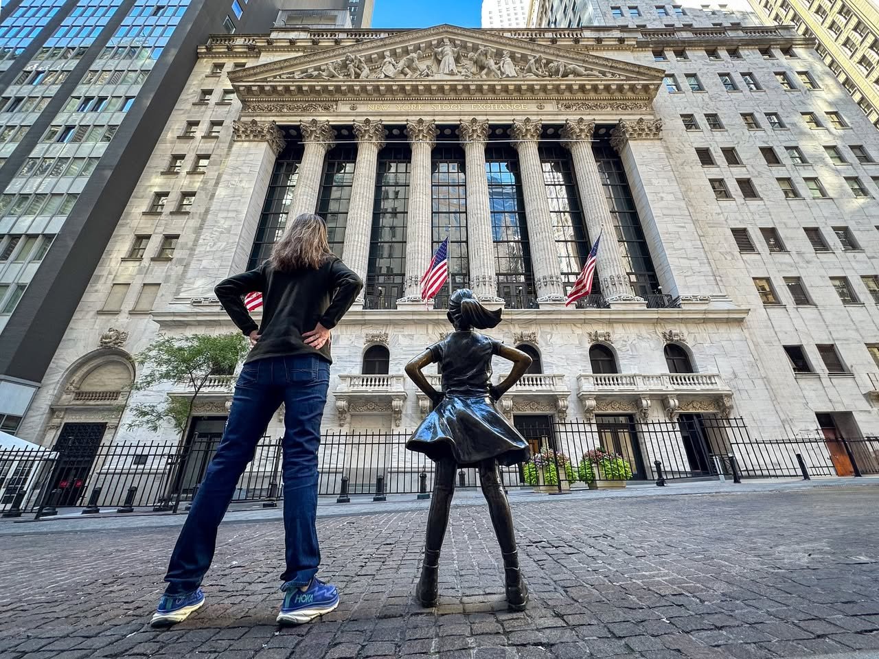 Financial District, Manhattan Two people posing with hands on hips in front of a historic building, one mimicking a nearby statue.
