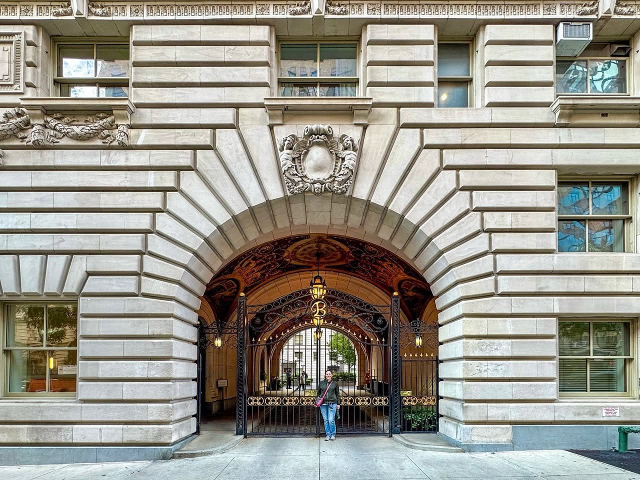 A grand stone archway leading into a historic building with intricate architectural details and a person walking through the passageway. The exterior facade features classical design elements and is a popular subject for urban photography enthusiasts.
