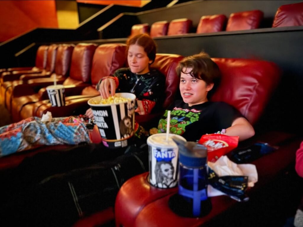 Enjoying popcorn and drinks while seated in an indoor movie theater.