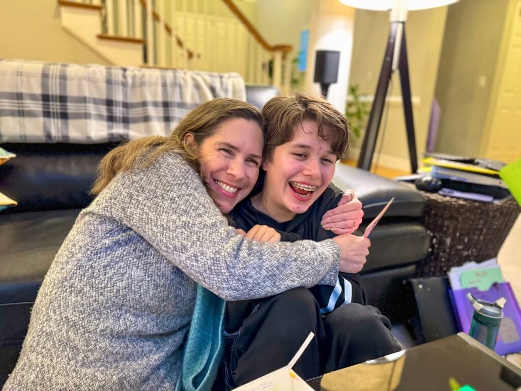 Two smiling people cuddling together in a cozy living room.