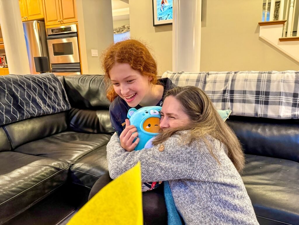 A snuggly moment on the black leather couch, sharing a blue bird toy and warm smiles.