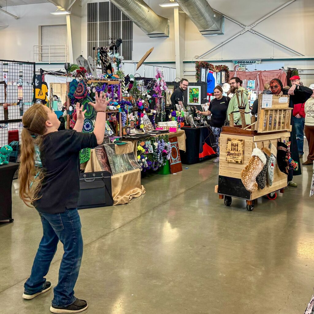 A person interactively observes handmade textiles and crafts at a local artisan fair in a spacious indoor venue.
