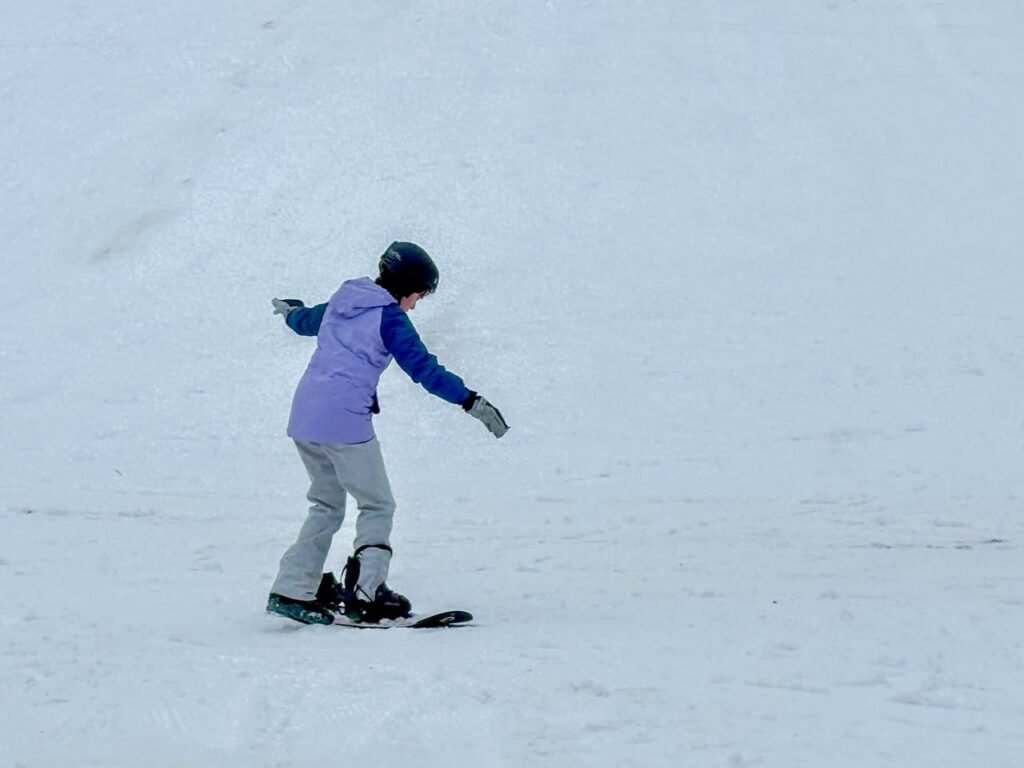 A young snowboarder riding down a snowy hill. Close-up of snowboarding boots on a snowboard.