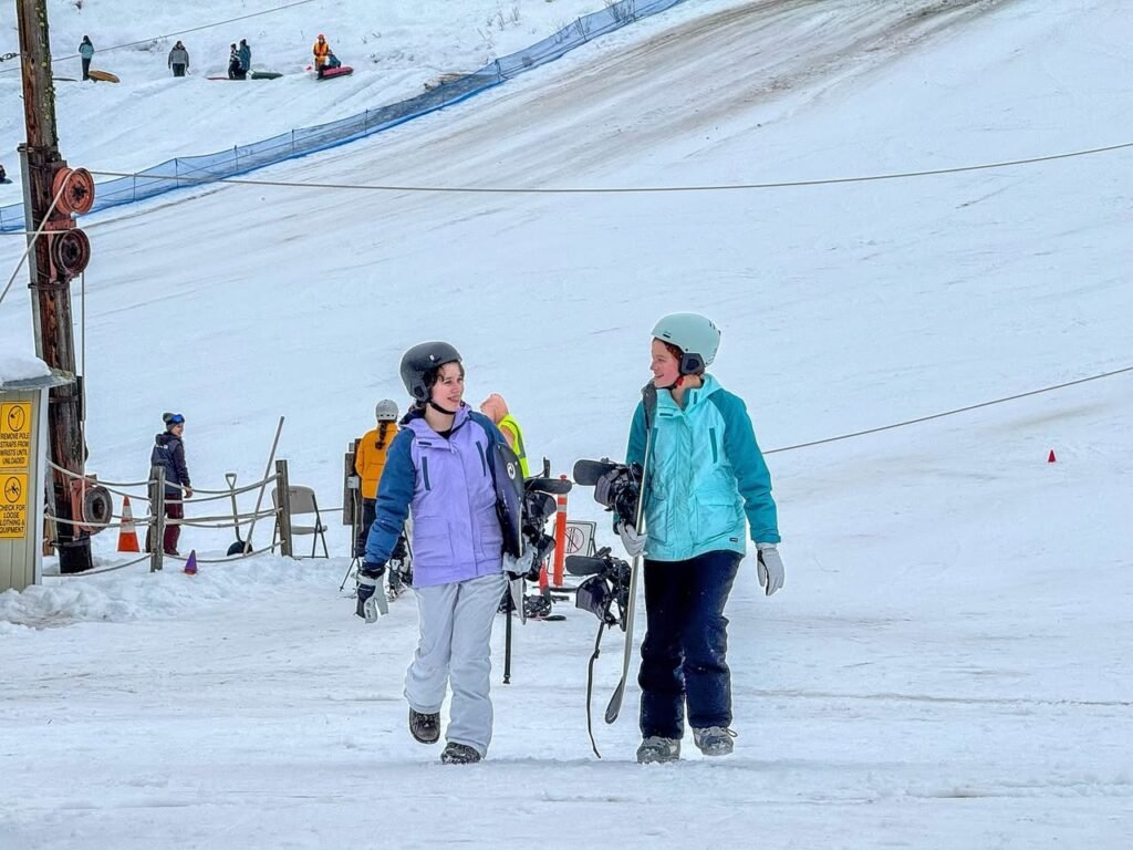 Two individuals skiing on a snowy slope, enjoying a winter day with a scenic mountain backdrop.