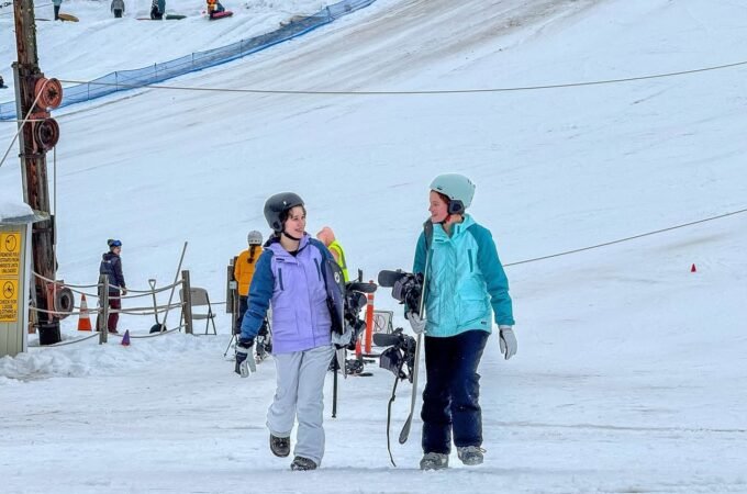 Two individuals skiing on a snowy slope, enjoying a winter day with a scenic mountain backdrop.