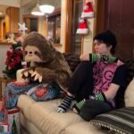 Snowboard Lessons A person sitting on a couch in a festive room with a giant sloth pillow and Christmas decorations in the background.