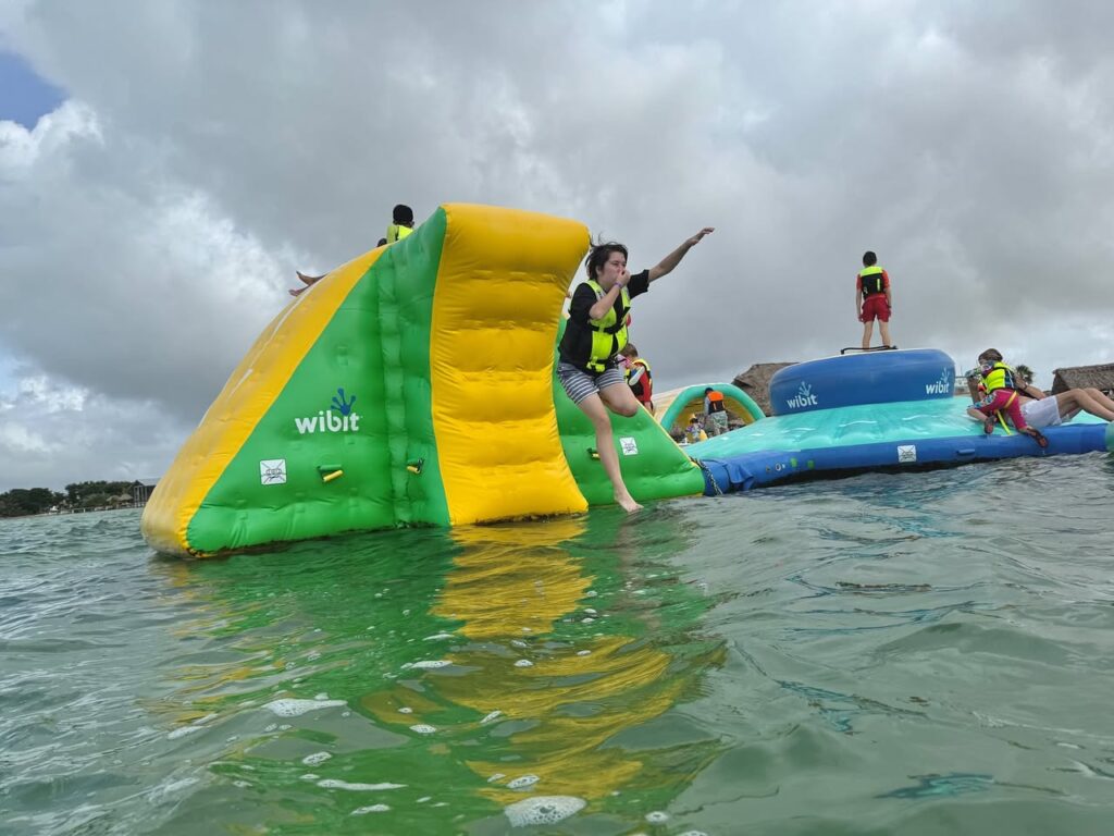 A vibrant photo collage of a floating water slide activity area with colorful inflatables.