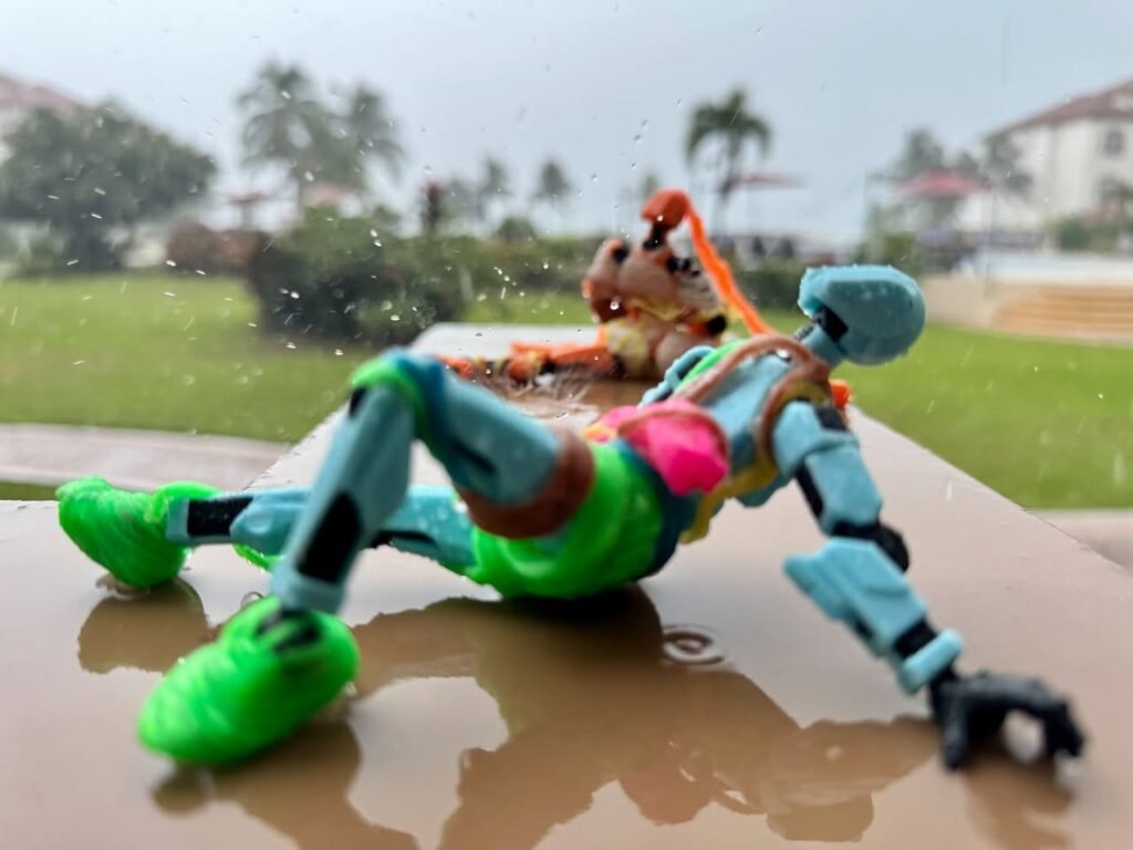 Colorful action figures enjoying a rainy day on a wet led. Blurry background shows grass and buildings.