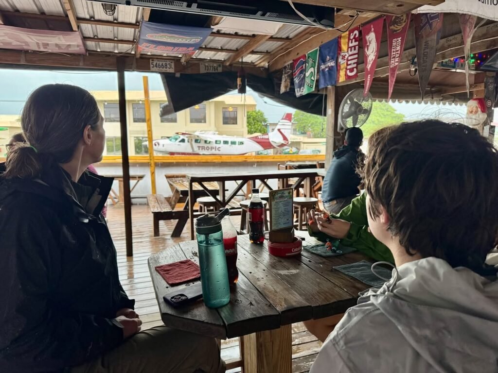 A group of travelers relaxing at an outdoor cafe with views of a parked airplane.