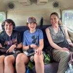 A happy family enjoys a train ride together, seated comfortably in the passenger car, looking forward to their next adventure.
