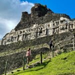 Tubing the Macal River A panoramic view of the Temple of the Sun at Machu Picchu, featuring stone ruins on a grassy hillside. Visitors walk along steps under a bright blue sky with scattered clouds.