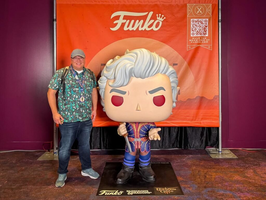A large Funko Pop statue standing next to a person in front of a Funko banner.