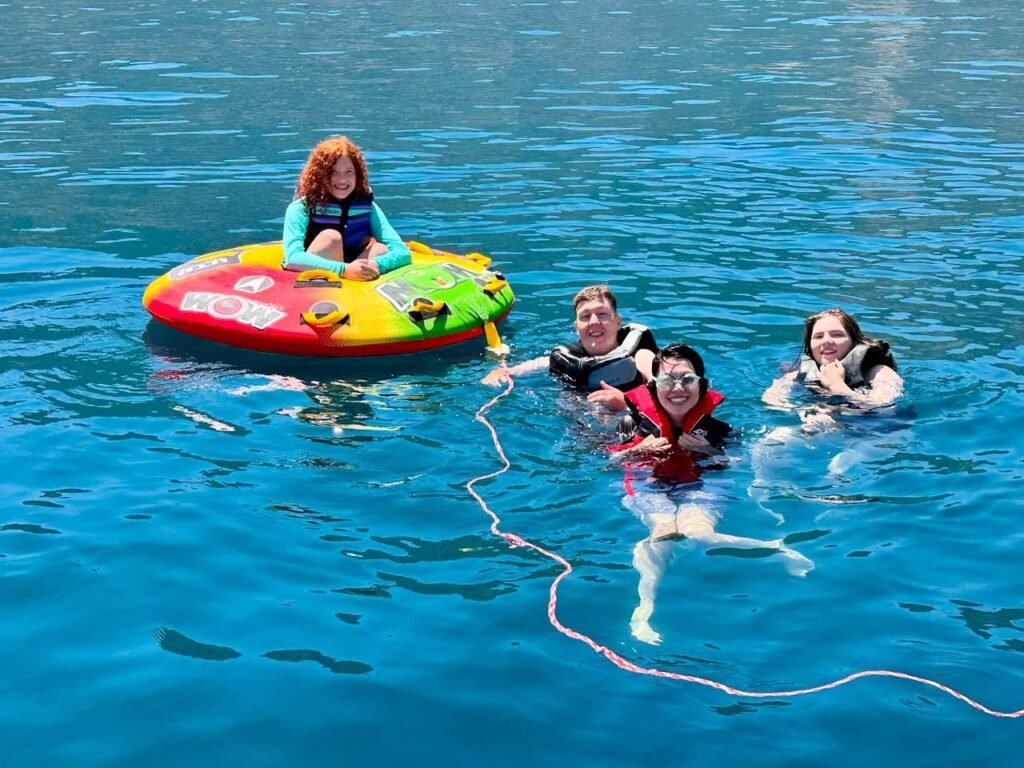 Family enjoying a day on the water with colorful inflatable rafts and swimming in clear blue ocean water, during a watersport adventure in the Pacific Northwest.