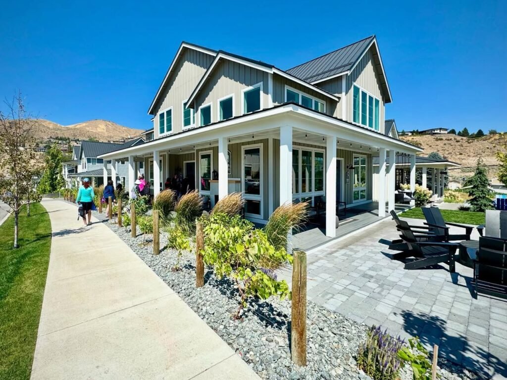 A modern house with a paved patio, garden, and a pathway leading to the entrance under a clear blue sky.
