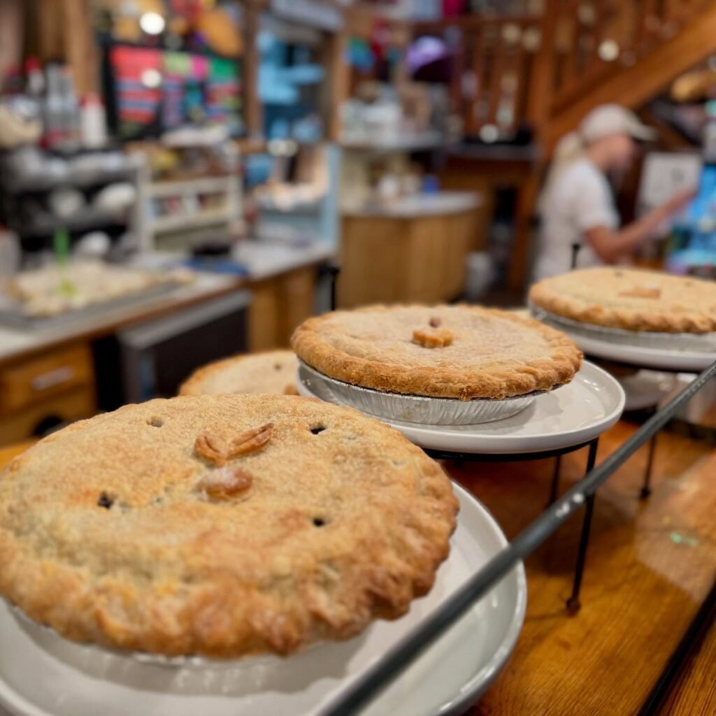 Golden-brown whole pies with lattice tops on plates at a rustic bakery or kitchen counter.