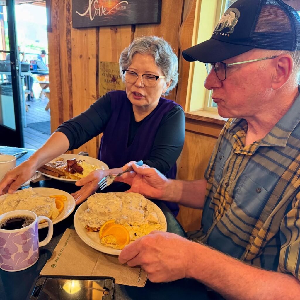 A couple enjoys a breakfast featuring waffles, eggs, and coffee in a cozy wooden diner.