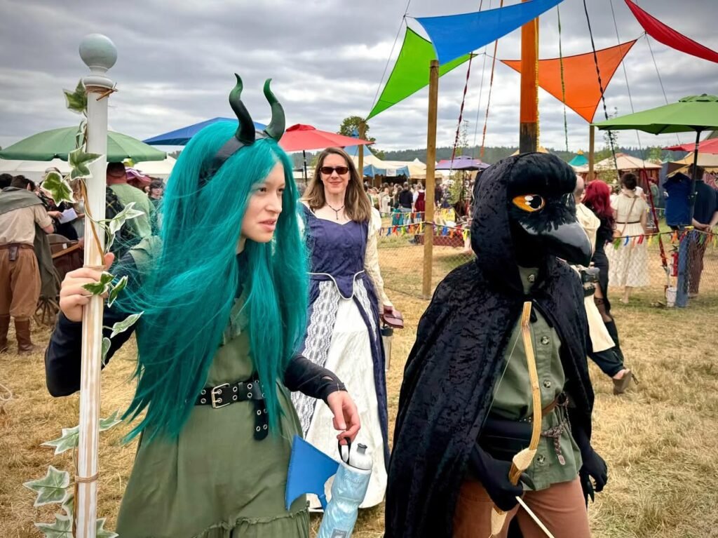 Attendees in elaborate dragon and raven costumes walking through a festival with colorful pennants.