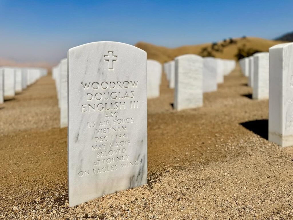 A close-up and aerial perspective of white marble cemetery headstones arranged in rows amidst a dry landscape.