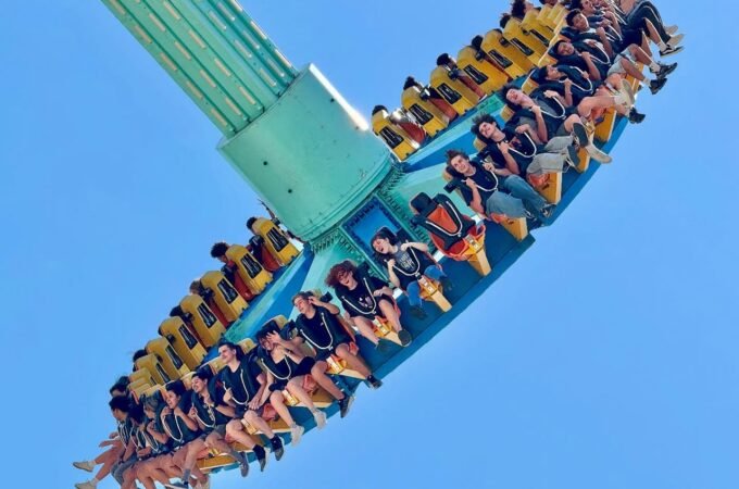 A spinning ride with riders enjoying the thrill against a clear blue sky.