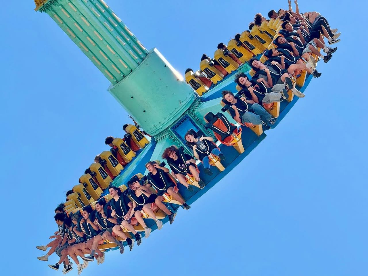 Six Flags Magic Mountain A spinning ride with riders enjoying the thrill against a clear blue sky.