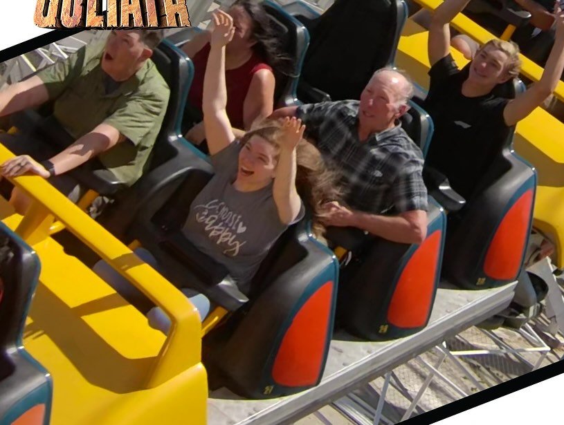 People enjoying a ride on a yellow and black roller coaster with expressions of thrill and joy.