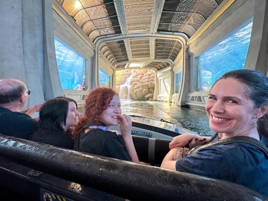 Visitors enjoy a ride through an underwater tunnel with clear views of marine life. A detailed view of the futuristic tunnel ceiling and water windows.