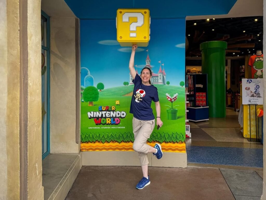A person jumping to touch a Super Nintendo World question block display at a theme park.