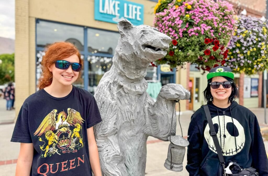 A group of people posing in front of a white bear statue on a shopping street.
