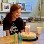 Swifts Night Out A birthday cake with lit candles and colorful decorations on a wooden kitchen counter