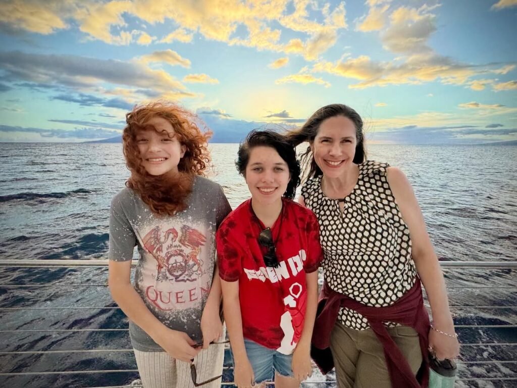Three individuals posing on a ship deck with a vast ocean and sunset sky background. The scene includes clear views of calm waters, a metal railing, and detailed attire for each person.