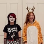 Hosmers Grove Birding Two costumed family members standing together in front of a white interior door. One wears a punk rock outfit with face paint, and the other a reindeer onesie.
