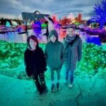 Happy Thanksgiving A family enjoys visiting a vibrant holiday light show. The festive atmosphere is highlighted by colorful LEDs and glowing trees.