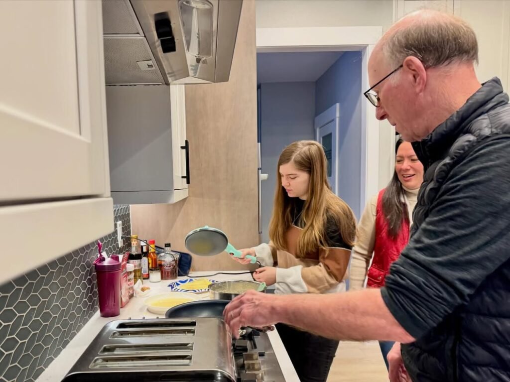 Family members cooking together in a kitchen with blue walls and modern appliances.