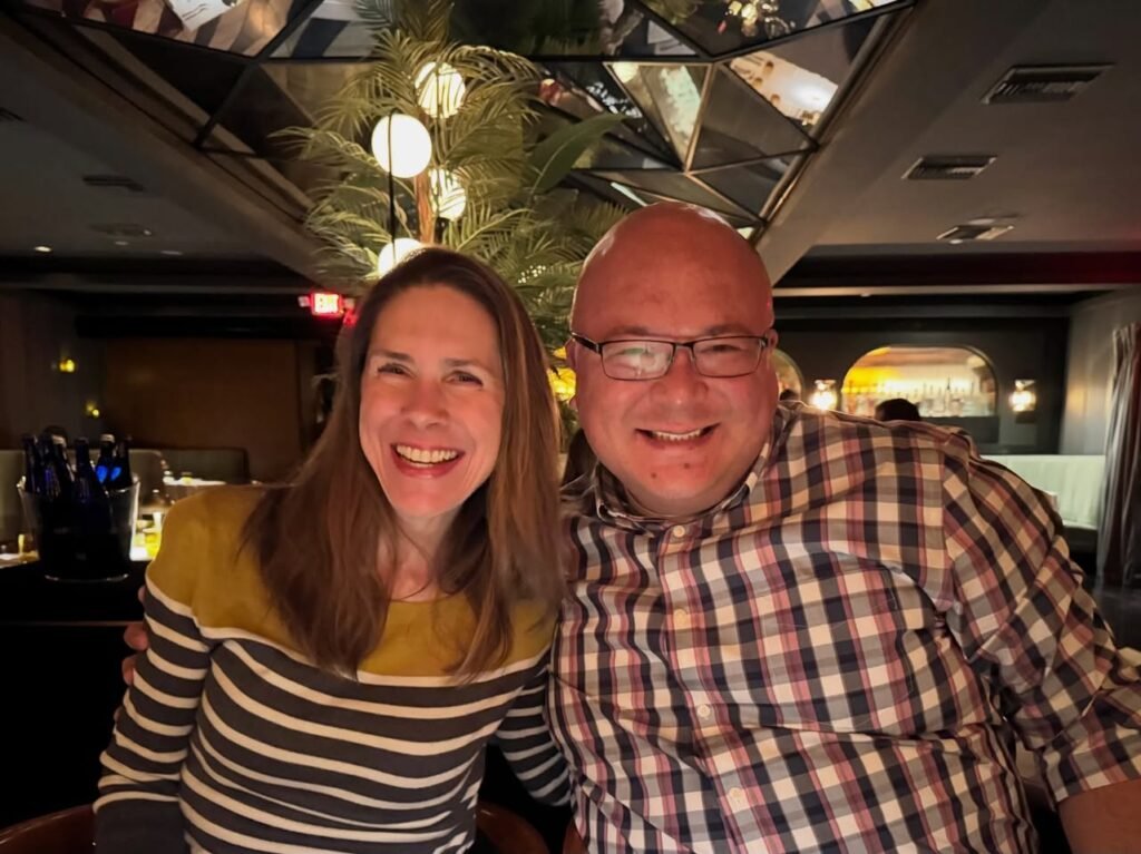 A smiling couple posing for a photo in a restaurant with geometric ceiling details.