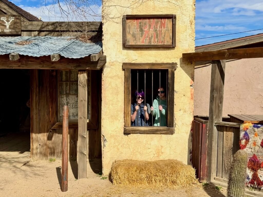 A rustic adobe house with wooden beams and vibrant textiles in a desert setting.