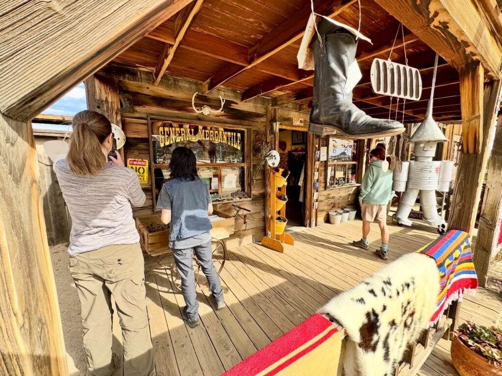 Visitors inside a rustic wooden building with a large boot suspended from the ceiling.