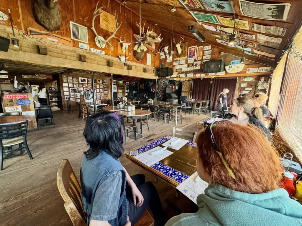 People seated at a table inside a rustic wooden establishment decorated with antlers and vintage memorabilia on the walls.