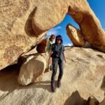 Heart Rock Two hikers pose beneath a massive natural rock arch on a sunny day.