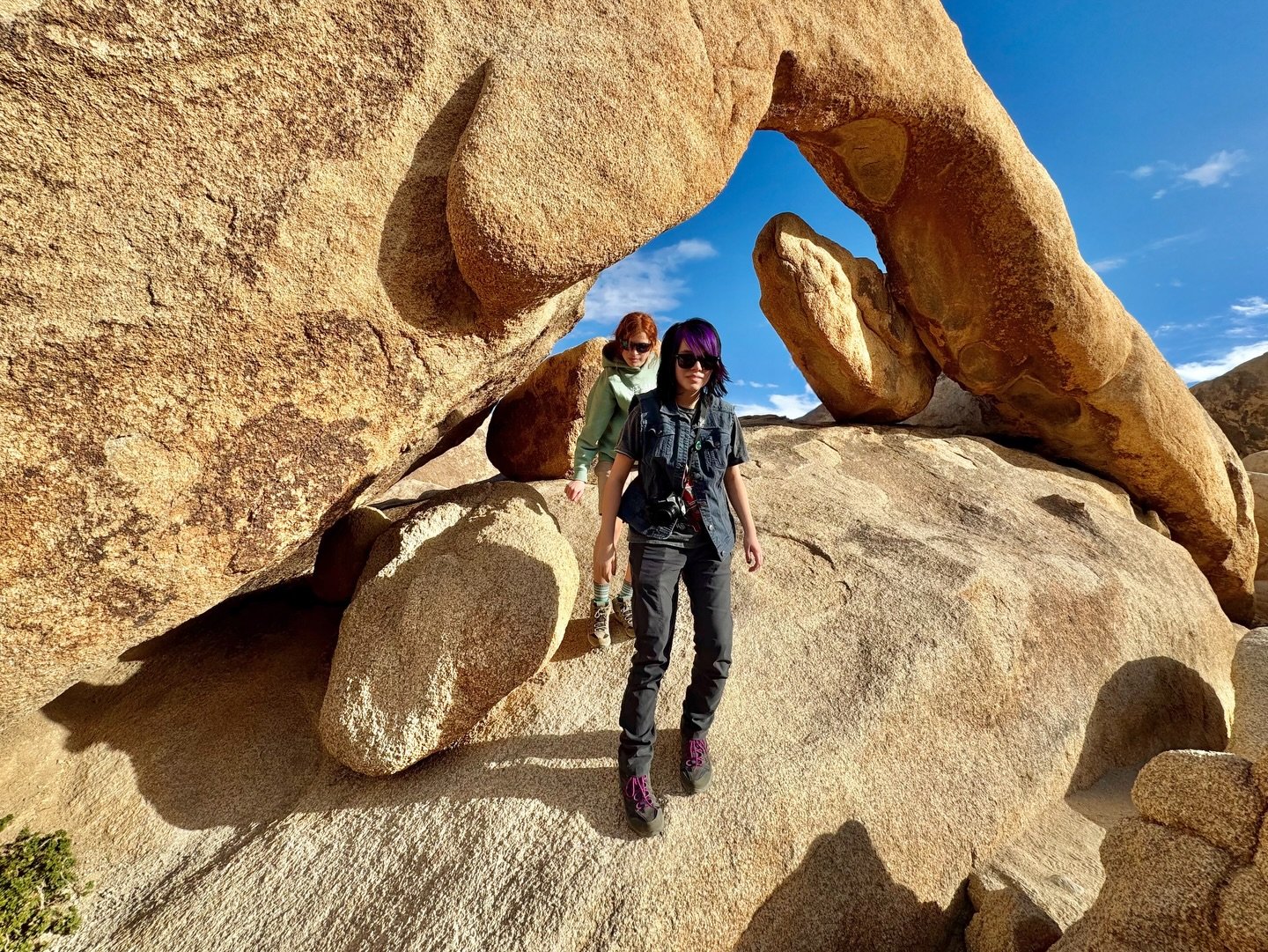 Arch Rock Two hikers pose beneath a massive natural rock arch on a sunny day.