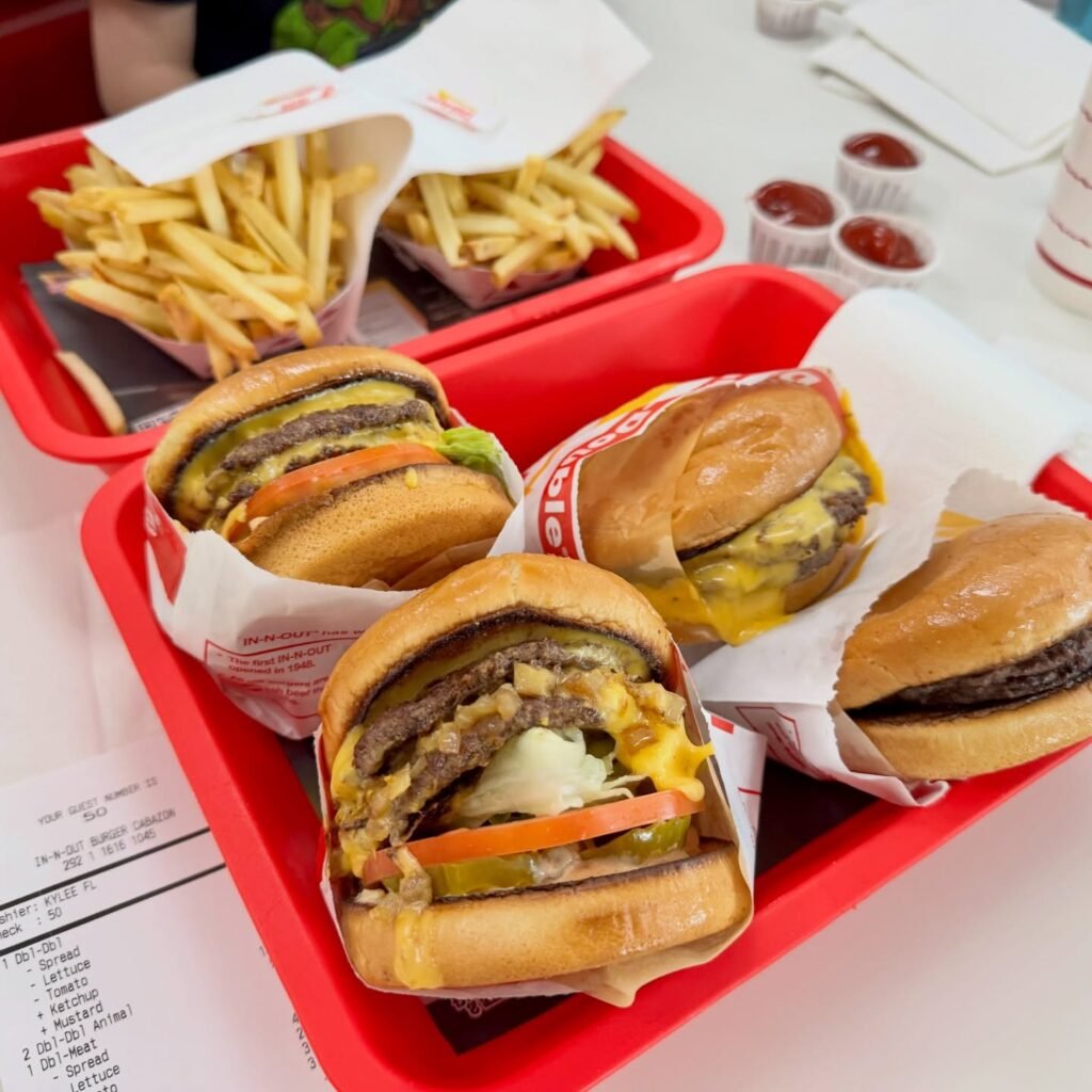 Red trays filled with sandwiches and golden fries, accompanied by small containers of ketchup and mustard.