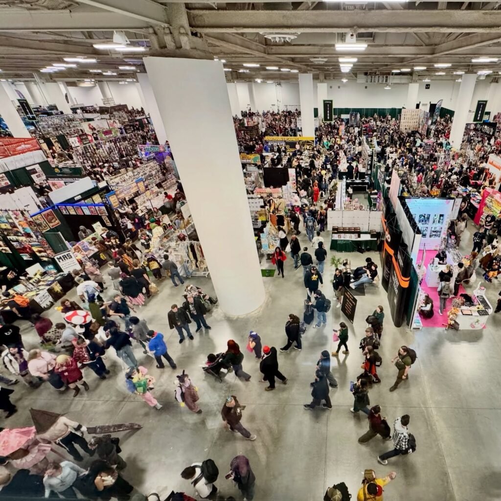 An elevated overhead view of a packed convention center filled with visitors and vendor booths.